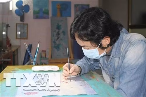 Họa sỹ Phan Tuấn Ngọc vẽ tranh với chủ đề "Hãy ở nhà". Ảnh: Thùy Dung - TTXVN