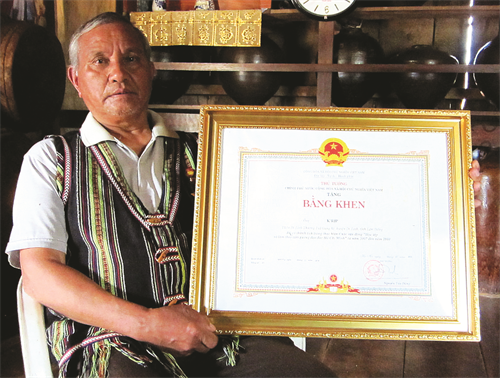 Già làng K’Brịp bên Bằng khen của Thủ tướng Chính phủ về thành tích học tập và làm theo tấm gương đạo đức Hồ Chí Minh