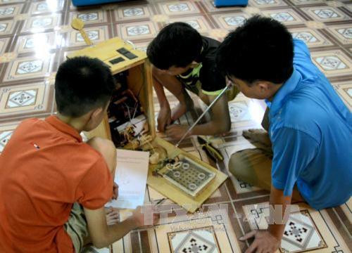 Ma Văn Hùng và Đào Minh Anh cùng thầy giáo hướng dẫn giới thiệu cơ chế hoạt động của "Quạt đa năng". Ảnh: Văn Dũng - TTXVN