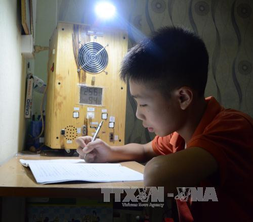 Ma Văn Hùng ngồi học bên cạnh "Quạt đa năng" do mình chế tạo nên. Ảnh: Văn Dũng - TTXVN