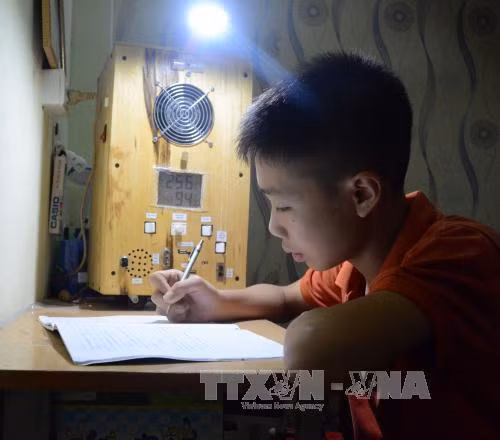 Ma Văn Hùng ngồi học bên cạnh "Quạt đa năng" do mình chế tạo nên. Ảnh: Văn Dũng - TTXVN