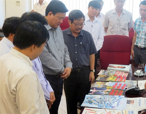 Đồng chí Đinh La Thăng xem Báo ảnh Dân tộc và Miền núi tại Phòng trưng bày báo và các ấn phẩm tại Cơ quan TTXVN khu vực phía Nam.