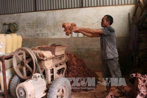 Công đoạn người thợ cho đất vào máy nhào cho mịn trước khi nặn tạo hình gốm. Ảnh: Thanh Thương - TTXVN Công đoạn người thợ cho đất vào máy nhào cho mịn trước khi nặn tạo hình gốm. Ảnh: Thanh Thương - TTXVN
