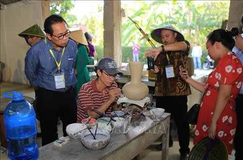 Du khách tham quan nghề làm gốm ở làng cổ Phước Tích. Ảnh: Hồ Cầu-TTXVN