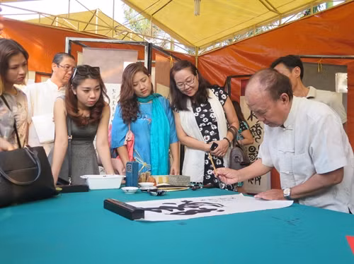 Nghệ nhân Trương Lộ thuộc Hội Văn học nghệ thuật các dân tộc thiểu số thành phố HCM đang cho chữ du khách