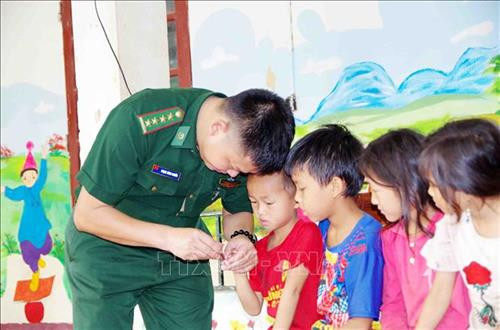 Cán bộ, chiến sỹ Đồn Biên phòng Pa Tần cắt móng tay và hướng dẫn cách vệ sinh thân thể cho các em học sinh trường Tiểu học Pa Tần. Ảnh: Công Tuyên - TTXVN