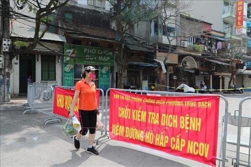 Cơ quan chức năng lắp đặt chốt kiểm soát ở ngã tư Trúc Bạch - Ngũ Xã, người dân tiếp tế thực phẩm cho người thân phải gửi qua trạm kiểm tra. Ảnh: Thành Đạt - TTXVN