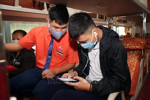 Hành khách tại bến xe Nước Ngầm (Hà Nội), được nhân viên nhà xe hướng dẫn khai báo y tế trên ứng dụng “Vietnam Health Declaration”. Ảnh: Danh Lam – TTXVN