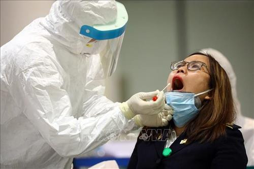 Nhân viên y tế lấy mẫu xét nghiệm của từng người ngay sau khi khách khai báo y tế và đo thân nhiệt tại sân bay Nội Bài . Ảnh: TTXVN