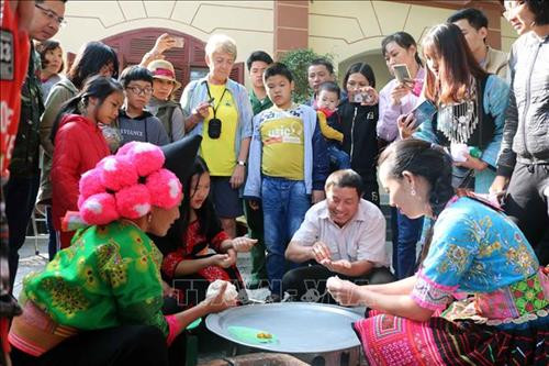Đồng bào dân tộc Mông hướng dẫn người tham gia chương trình cách làm bánh dày truyền thống. Ảnh: Diệp Anh - TTXVN