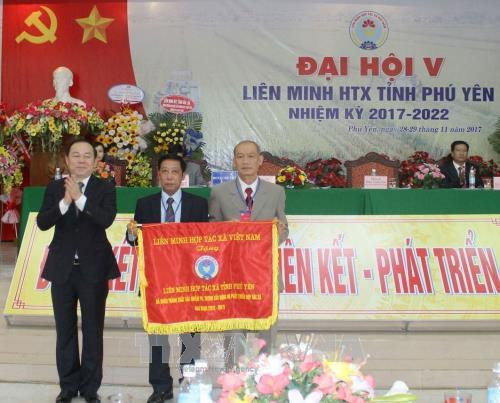 Ông Nguyễn Ngọc Bảo (trái), Chủ tịch Liên minh HTX Việt Nam, trao Cờ thi đua xuất sắc cho Liên minh HTX tỉnh Phú Yên. Ảnh: Xuân Triệu - TTXVN