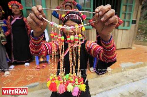 Chiếc vòng làm bằng nhựa màu nâu đỏ dùng để cố định những nếp tóc là lớp đầu tiên của khăn đội đầu người La Hủ. Lớp khăn thứ hai của chiếc khăn đội đầu của những người phụ nữ La Hủ. Nó được làm bằng vài nhiều màu và được gấp lại trước khi đội lên. Người phụ nữ La Hủ cố định lớp thứ 2 của chiếc khăn truyền thống. Sau khi đội lớp thứ 2, họ dùng dải dây thun vấn, che hết phần tóc còn lại. Lớp thứ 3 của chiếc khăn đội đầu có những sợi tua rua dài che phía sau đầu những người phụ nữ La Hủ. Thường từ lớp thứ 3 của chiếc khăn, họ cần một người khác giúp để hoàn thành chiếc khăn đội đầu sao cho đẹp nhất. Dải tua rua là lớp cuối cùng trên chiếc khăn đội đầu. Người con gái La Hủ luôn thường nuôi tóc dài để vấn tóc, đội chiếc khăn truyền thống rất cầu kỳ này. Chiếc khăn đội đầu của người phụ nữ La Hủ nhìn từ phía sau. Hai thế hệ phụ nữ người La Hủ ở Bum Tở. Vào ngày thường phụ nữ La Hủ mặc chiếc áo tà dài có màu đen truyền thống. Nhưng trong dịp lễ họ mặc thêm một chiếc áo khoác ngắn được đính trang trí khá cầu kỳ. Chiếc khăn đội đầu sặc sỡ là điểm nhấn làm nên sự khác biệt trong trang phục của người La Hủ. Những dải tua rua trên chiếc khăn đội đầu tạo nên nét rất sinh động trong trang phục của người phụ nữ La Hủ. Những cô gái La Hủ ở xã Bum Tở, huyện Mường Tè, tỉnh Lai Châu trong trang phục truyền thống đang tập múa, hát trong sân nhà văn hóa của bản.