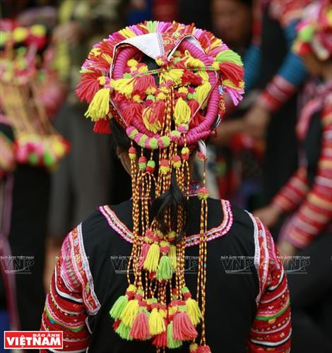 Chiếc vòng làm bằng nhựa màu nâu đỏ dùng để cố định những nếp tóc là lớp đầu tiên của khăn đội đầu người La Hủ. Lớp khăn thứ hai của chiếc khăn đội đầu của những người phụ nữ La Hủ. Nó được làm bằng vài nhiều màu và được gấp lại trước khi đội lên. Người phụ nữ La Hủ cố định lớp thứ 2 của chiếc khăn truyền thống. Sau khi đội lớp thứ 2, họ dùng dải dây thun vấn, che hết phần tóc còn lại. Lớp thứ 3 của chiếc khăn đội đầu có những sợi tua rua dài che phía sau đầu những người phụ nữ La Hủ. Thường từ lớp thứ 3 của chiếc khăn, họ cần một người khác giúp để hoàn thành chiếc khăn đội đầu sao cho đẹp nhất. Dải tua rua là lớp cuối cùng trên chiếc khăn đội đầu. Người con gái La Hủ luôn thường nuôi tóc dài để vấn tóc, đội chiếc khăn truyền thống rất cầu kỳ này. Chiếc khăn đội đầu của người phụ nữ La Hủ nhìn từ phía sau. Hai thế hệ phụ nữ người La Hủ ở Bum Tở. Vào ngày thường phụ nữ La Hủ mặc chiếc áo tà dài có màu đen truyền thống. Nhưng trong dịp lễ họ mặc thêm một chiếc áo khoác ngắn được đính trang trí khá cầu kỳ. Chiếc khăn đội đầu sặc sỡ là điểm nhấn làm nên sự khác biệt trong trang phục của người La Hủ. Những dải tua rua trên chiếc khăn đội đầu tạo nên nét rất sinh động trong trang phục của người phụ nữ La Hủ. Những cô gái La Hủ ở xã Bum Tở, huyện Mường Tè, tỉnh Lai Châu trong trang phục truyền thống đang tập múa, hát trong sân nhà văn hóa của bản.