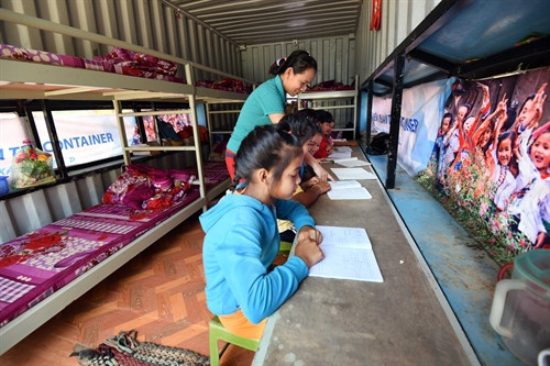 Cô giáo chỉ dẫn các em học bài tại nhà ở bán trú.