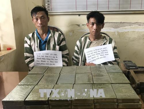 Hai đối tượng Lầu A Chừ và Giàng A Mai cùng tang vật vụ án. Ảnh: TTXVN phát. Hai đối tượng Lầu A Chừ và Giàng A Mai cùng tang vật vụ án. Ảnh: TTXVN phát.