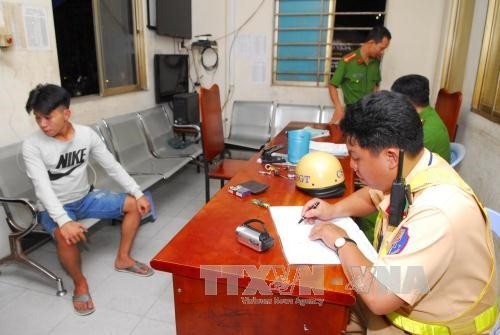 Cảnh sát giao thông lập biên bản xử lý chủ phương tiện xe máy. Ảnh: Mạnh Linh-TTXVN