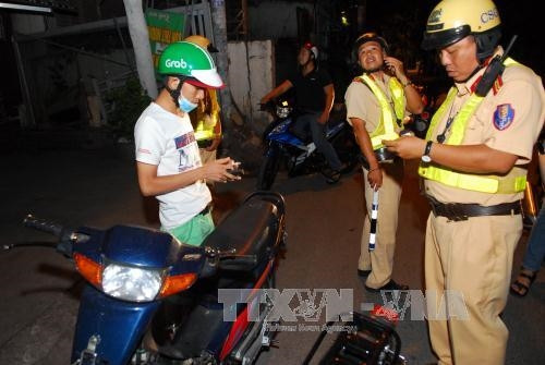 Lực lượng CSGT kiểm tra giấy tờ của chủ phương tiện xe máy. Ảnh: Mạnh Linh-TTXVN