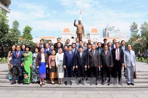 Bí thư Thành ủy, Đô trưởng Thủ đô Viêng Chăn Sinlavong Khoutphaythune, Chủ tịch UBND Thành phố Hồ Chí Minh Nguyễn Thành Phong và các đại biểu hai thành phố chụp ảnh chung tại Tượng đài Chủ tịch Hồ Chí Minh. Ảnh: Thanh Vũ-TTXVN