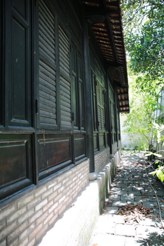 Ngôi nhà cổ được xây từ năm 1799 - Ảnh : Ngọc Tiến. Ngôi nhà được chúa Nguyễn Ánh cho xây dựng vào năm 1799 theo lối kiến trúc truyền thống của Việt Nam với ba gian, hai chái làm nơi trú ngụ cho Giám mục Bá Đa Lộc (quốc tịch Pháp, sinh năm 1741), người dạy học cho hoàng tử Nguyễn Cảnh lúc đó. Ban đầu ngôi nhà được xây dựng bên phần đất của Thảo Cầm Viên bây giờ. Năm 1911, khi Tòa Tổng Giám mục hiện nay được xây dựng hoàn thành, ngôi nhà dời về đây và được giữ gìn, bảo quản đến ngày hôm nay - Ảnh : Ngọc Tiến. Qua những lần di dời trước đó, phần nền đất làm cho cột trụ ngôi nhà bị hư hỏng. Sau đợt trùng tu nền nhà được nâng cao hơn, cột trụ ngôi nhà được đặt trên những tảng đá để đỡ một phần tải trọng và chắc chắn hơn như nguyên bản ngôi nhà ban đầu - Ảnh : Ngọc Tiến. Dàn rui lách, kèo và hệ thống vách được xếp đặt một cách tinh xảo - đó là nét độc đáo và giá trị to lớn về lịch sử và văn hóa ngôi nhà - Ảnh : Ngọc Tiến. Mái nhà được lợp ngói âm dương với những họa tiết hoa văn viền tinh xảo. Hiện nay, lớp ngói đỏ đã được làm mới thay cho lớp ngói cũ rêu phong - Ảnh : Ngọc Tiến. Các cánh cửa làm bằng gỗ quý, hoa văn được điêu khắc tinh xảo tạo thêm nét cổ kính cho mặt tiền của căn nhà - Ảnh : Ngọc Tiến. Ngôi nhà được làm hoàn toàn bằng gỗ quý, khung nhà được liên kết chặt chẽ với nhau hoàn toàn bằng kỹ thuật ghép mộng của những nghệ nhân thời xưa. Hoàn toàn không dùng bất cứ cây đinh nào nhưng ngôi nhà vẫn đứng vững qua hàng trăm năm - Ảnh : Ngọc Tiến. Các nét chạm khắc trên những bộ cửa, vách nhà chưa bị bào mòn và còn nguyên vẹn - Ảnh : Ngọc Tiến. Họa tiết trang trí được khắc họa tỉ mỉ, công phu đặt ngay cửa chính diện tạo sự cân đối và cổ kính, thể hiện nét sáng tạo độc đáo - Ảnh : Ngọc Tiến. Nhiều vật dụng trong nhà như bàn, ghế, tủ, bình phong... vẫn được giữ nguyên vẹn và còn khá tốt. Những chùm đèn được thay mới vì đèn cũ đã hư hỏng, không thể sử dụng được nữa - Ảnh : Ngọc Tiến.