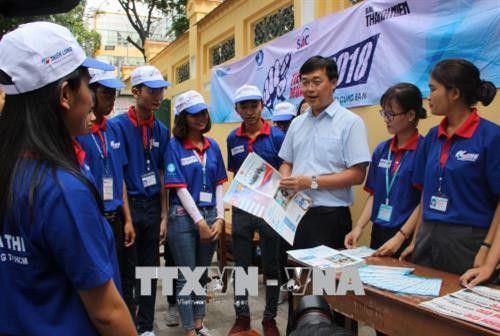 Bí thư thứ nhất Trung ương Đoàn Lê Quốc Phong (áo sơ mi xanh) thăm hỏi sinh viên tình nguyện tại điểm thi Trường trung học phổ thông Marie Curie. Ảnh: Xuân Dự - TTXVN