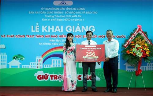 Đại diện Công ty Honda Việt Nam và Ban An toàn Giao thông tỉnh An Giang trao bảng tượng trưng tặng 256 mũ bảo hiểm đạt chuẩn cho học sinh lớp 1 trường Tiểu học Chu Văn An, phường Mỹ Xuyên, thành phố Long Xuyên. Ảnh: Công Mạo - TTXVN Đại diện Công ty Honda Việt Nam và Ban An toàn Giao thông tỉnh An Giang trao bảng tượng trưng tặng 256 mũ bảo hiểm đạt chuẩn cho học sinh lớp 1 trường Tiểu học Chu Văn An, phường Mỹ Xuyên, thành phố Long Xuyên. Ảnh: Công Mạo - TTXVN