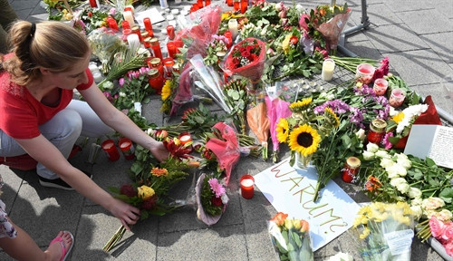 Thắp nến và đặt hoa tưởng niệm các nạn nhân vụ xả súng gần trung tâm Olympia ngày 23/7. AFP/ TTXVN