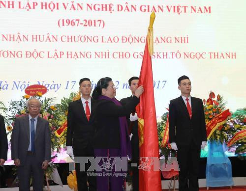 Phó Chủ tịch Thường trực Quốc hội Tòng Thị Phóng gắn Huân chương Lao động hạng Nhì lên lá cờ truyền thống của Hội Văn nghệ Dân gian Việt Nam. Ảnh: Phương Hoa – TTXVN