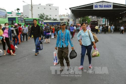 Người dân lỉnh khỉnh đồ đạc xuống bến xe Miền Tây sau lễ. Ảnh: Mạnh Linh-TTXVN