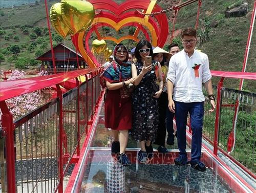 Du khách tham quan và trải nghiệm cầu kính tình yêu tại Khu du lịch sinh thái thác Dải Yếm, huyện Mộc Châu, tỉnh Sơn La. Ảnh: TTXVN