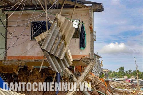 Một căn nhà bị sụp hoàn toàn xuống sông, chỉ còn lại phần vách nằm chơi vơi