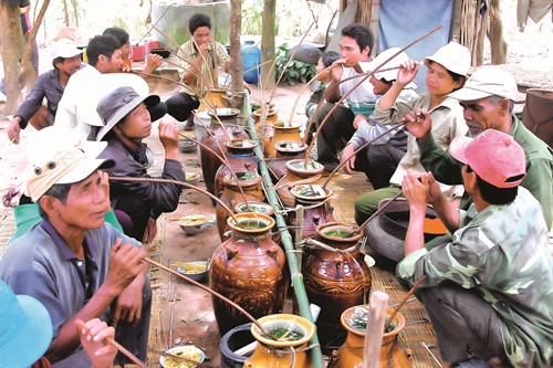 Dân làng thưởng thức rượu cần đựng trong những chiếc ghè tại lễ mừng nhà mới