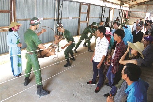 Thuyết minh viên Võ Thị Thu Hà giới thiệu với du khách về các hình thức tra tấn dã man tù binh thông qua các cảnh trí lịch sử được phục dựng sinh động Thuyết minh viên Võ Thị Thu Hà giới thiệu với du khách về các hình thức tra tấn dã man tù binh thông qua các cảnh trí lịch sử được phục dựng sinh động