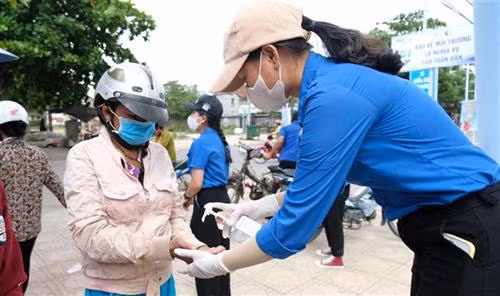 Tất cả người đến nhận gạo đều được sát khuẩn tay và đeo khẩu trang, xếp hàng theo thứ tự. Ảnh: Nguyễn Dũng – TTXVN