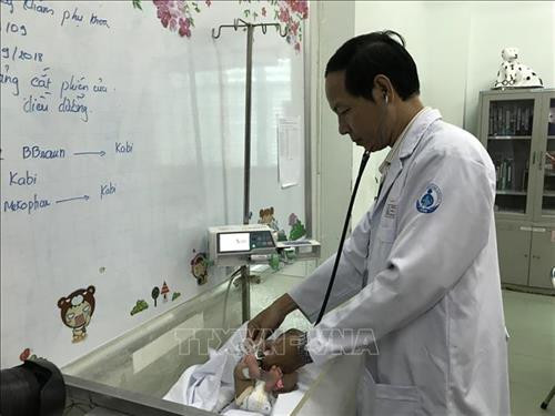 Bác sỹ Nguyễn Kiến Mậu, Trưởng khoa Hồi sức sơ sinh, Bệnh viện Nhi đồng 1 Thành phố Hồ Chí Minh đang kiểm tra tổng trạng cho bệnh nhi. Ảnh: Đinh Hằng - TTXVN