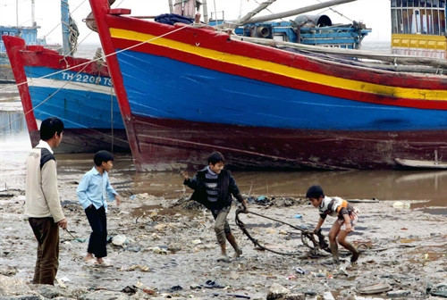 Trẻ em xã Ngư Lộc nhặt phế thải trên bãi biển. Ảnh: Dương Ngọc - TTXVN.