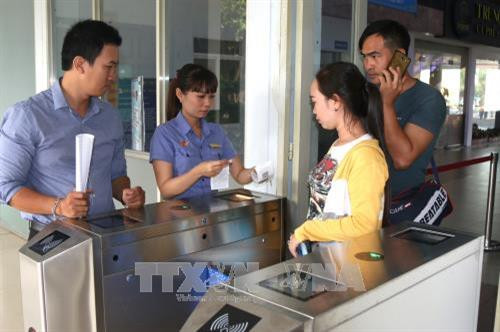 Hướng dẫn hành khách tại cổng soát vé tự động. Ảnh: Trần Xuân Tình-TTXVN