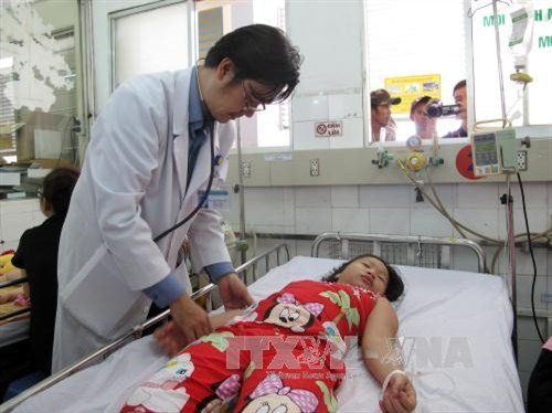 Bác sĩ Nguyễn Minh Tuấn, Trưởng khoa Sốt xuất huyết, Bệnh viện Nhi đồng 1 đang khám cho bệnh nhi sốt xuất huyết. Ảnh: Đinh Hằng - TTXVN
