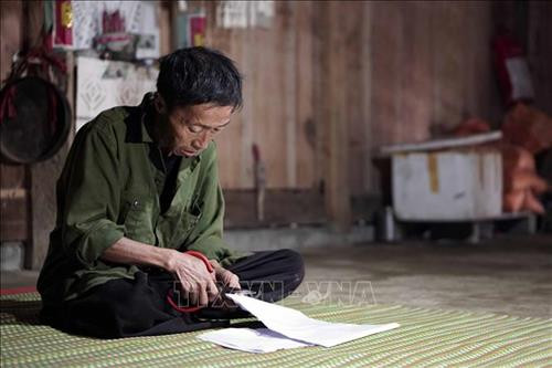 Nghi thức cắt giấy để dán lên các công cụ lao động của người Mông. Ảnh: Hữu Quyết - TTXVN Nghi thức cắt giấy để dán lên các công cụ lao động của người Mông. Ảnh: Hữu Quyết - TTXVN