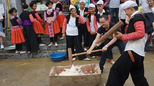 Du khách thích thú tham gia trải nghiệm giã bánh giầy cùng đồng bào dân tộc Mông. Ảnh: Hoàng Tâm