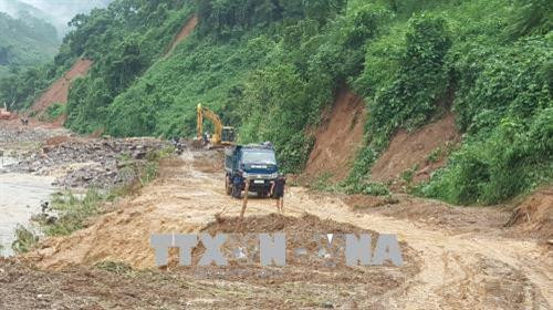 Các phương tiện và lực lượng cứu hộ đang nỗ lực thông các tuyến đường bị sạt lở tại huyện Văn Chấn. Ảnh Tuấn Anh - TTXVN