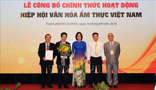 Bà Nguyễn Thị Tuyết Mai (Vụ Tổ chức Phi chính phủ, Bộ Nội vụ) trao Quyết định của Bộ Nội vụ phê duyệt Điều lệ Hiệp hội văn hóa ẩm thực Việt Nam cho đại diện Ban Chấp hành Hiệp hội. Ảnh: Xuân Khu-TTXVN