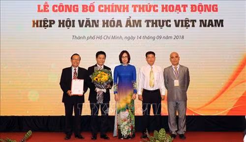 Bà Nguyễn Thị Tuyết Mai (Vụ Tổ chức Phi chính phủ, Bộ Nội vụ) trao Quyết định của Bộ Nội vụ phê duyệt Điều lệ Hiệp hội văn hóa ẩm thực Việt Nam cho đại diện Ban Chấp hành Hiệp hội. Ảnh: Xuân Khu-TTXVN