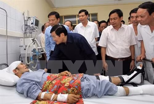 Chủ tịch nước Trương Tấn Sang đến thăm, tặng quà cho anh Cao Văn Vỹ, người duy nhất còn sống sót trong sự cố lở đất làm sập nhà, sáng 28/7. Ảnh: Nguyễn Khang/TTXVN