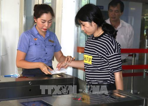 Hướng dẫn hành khách tại cổng soát vé tự động. Ảnh: Trần Xuân Tình-TTXVN