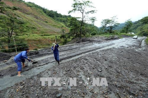 Bùn đất tràn xuống mặt đường Quốc lộ 12 gây khó khăn vất vả cho các đơn vị thi công nhằm thông tuyến giao thông. Ảnh: Phan Tuấn Anh – TTXVN