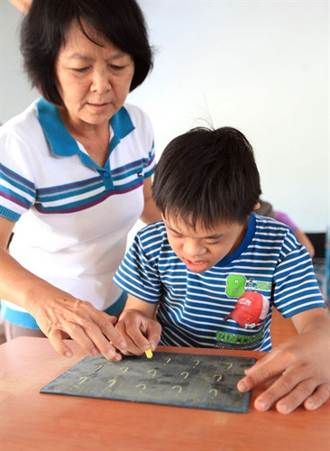 Các cô trong Trung tâm đang hướng dẫn các em viết chữ,