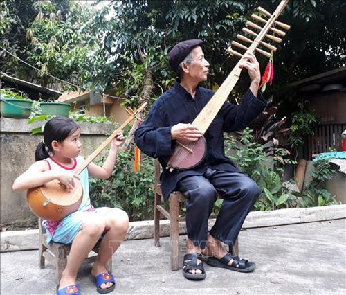 Nghệ nhân Dương Văn Thục truyền dạy cách đàn tính, hát then cho người cháu của mình. Ảnh: Đức Hiếu - TTXVN
