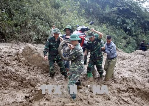 Cán bộ, chiến sỹ tham gia vận chuyển phương tiện giao thông giúp dân qua những đoạn đường bị sạt lở mất đường do mưa lũ gây ra trên địa bàn. Ảnh: TTXVN phát