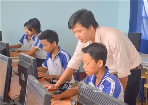 Thầy Phan Khánh Duy hướng dẫn các em học tập môn Tin học. Ảnh: Nhật Bình - TTXVN.