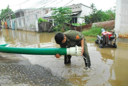 Lực lượng phường Hiệp Bình Chánh triển khai máy bơm để hút nước ra ngoài. Ảnh: Mạnh Linh-TTXVN
